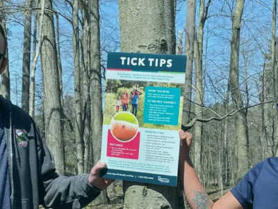 Conservation area authority and health unit staff hang up tick poster