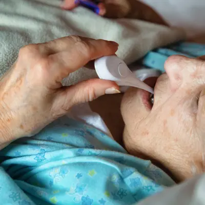 Elderly woman having her temperature taken in bed.